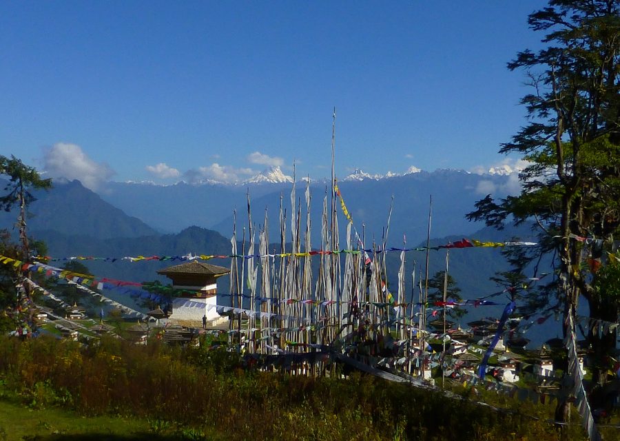 Prayer flag poles on a ridge with a small chorten and the snow peaks of the eastern Himalayas behind