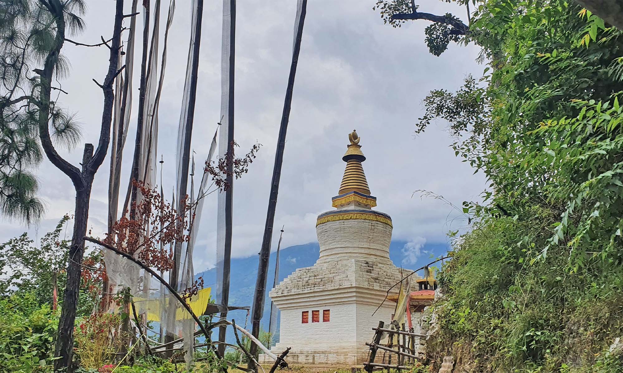 A chorten and prayer flag poles on the hillside at Mongar